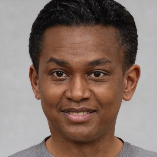 Joyful black young-adult male with short  black hair and brown eyes