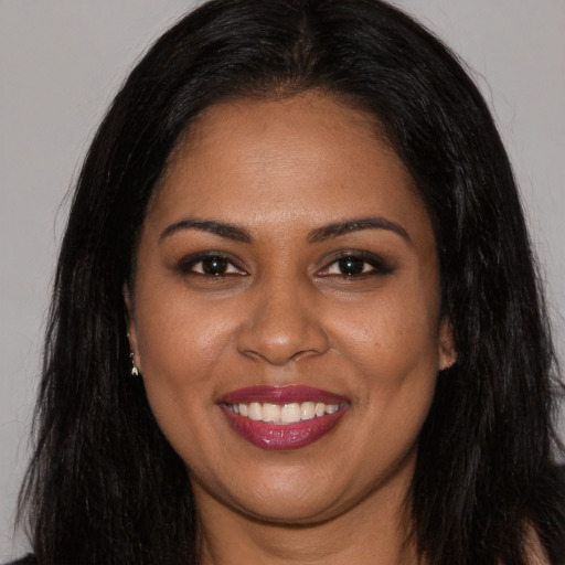 Joyful black young-adult female with long  brown hair and brown eyes