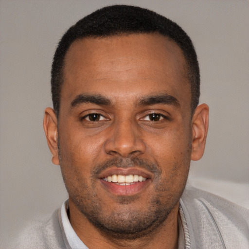 Joyful black young-adult male with short  brown hair and brown eyes