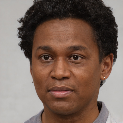 Joyful black young-adult male with short  brown hair and brown eyes