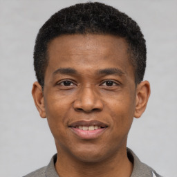 Joyful black young-adult male with short  brown hair and brown eyes