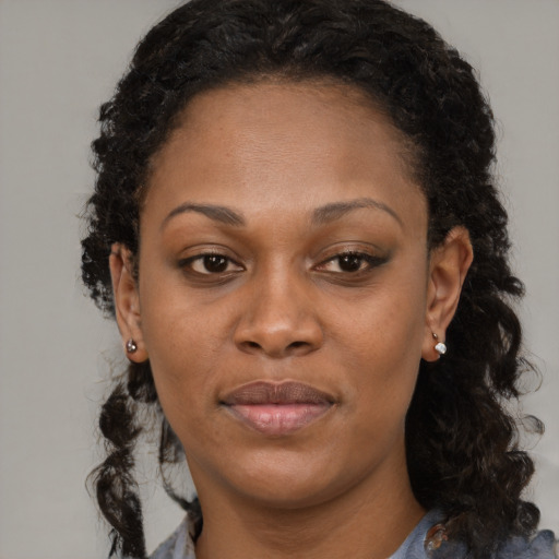 Joyful black young-adult female with long  brown hair and brown eyes