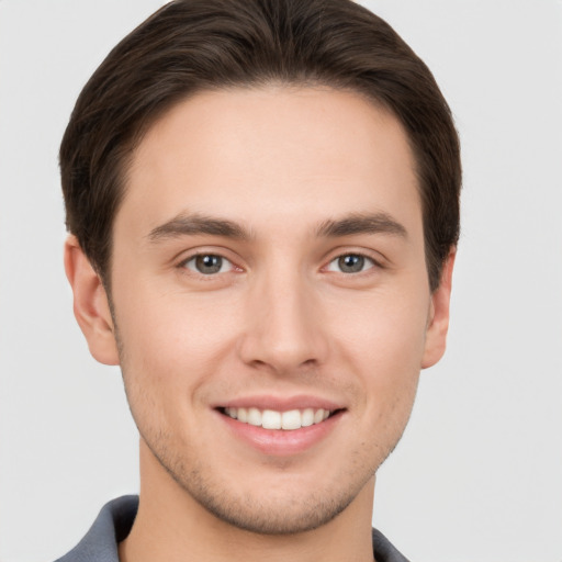 Joyful white young-adult male with short  brown hair and grey eyes