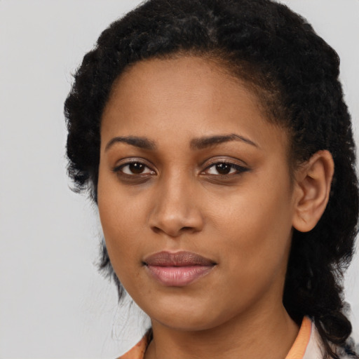 Joyful black young-adult female with long  black hair and brown eyes