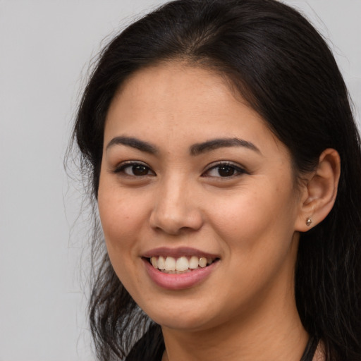 Joyful latino young-adult female with long  brown hair and brown eyes