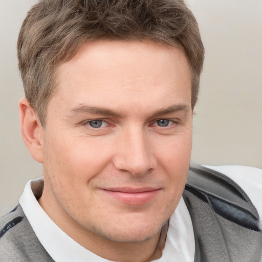 Joyful white young-adult male with short  brown hair and grey eyes