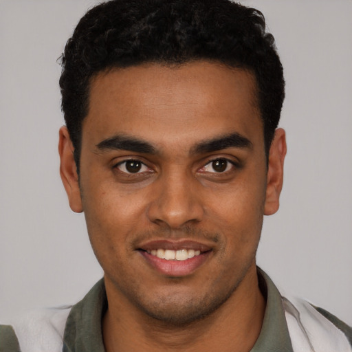 Joyful black young-adult male with short  black hair and brown eyes