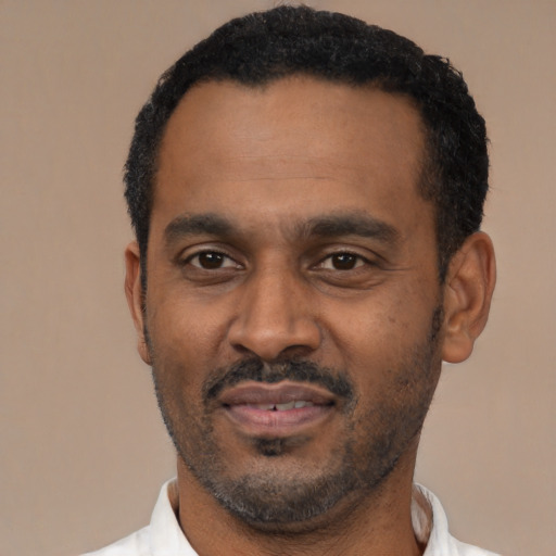Joyful black adult male with short  black hair and brown eyes