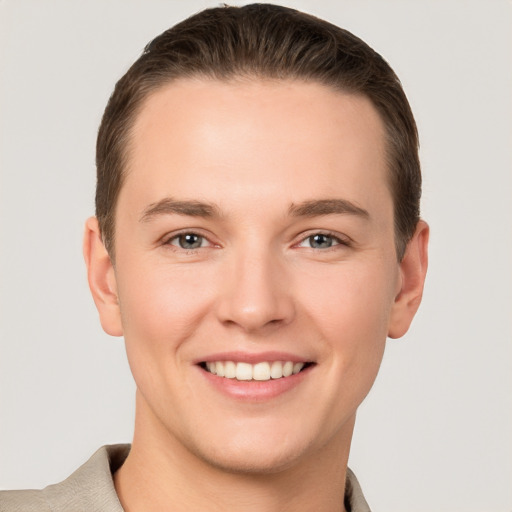 Joyful white young-adult male with short  brown hair and grey eyes