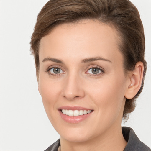 Joyful white young-adult female with medium  brown hair and grey eyes