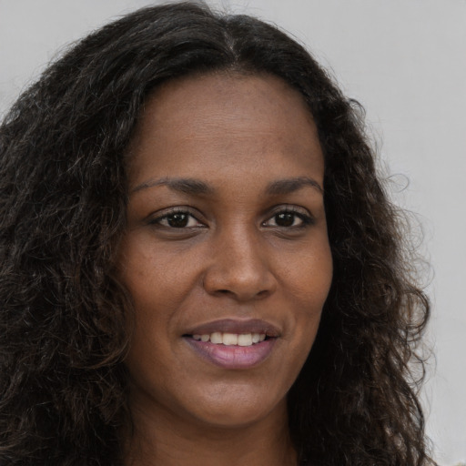 Joyful black young-adult female with long  brown hair and brown eyes