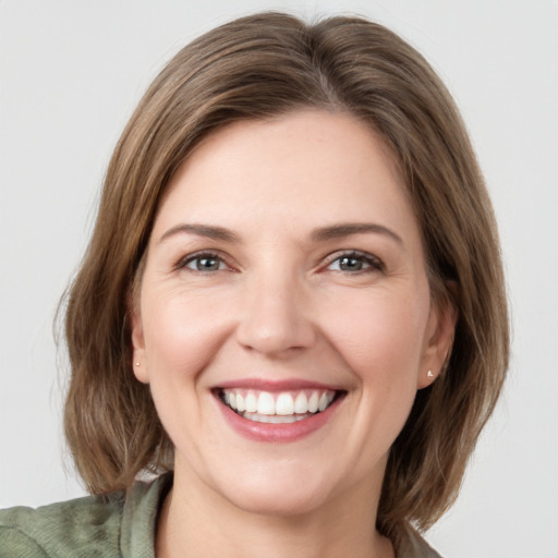 Joyful white young-adult female with medium  brown hair and grey eyes