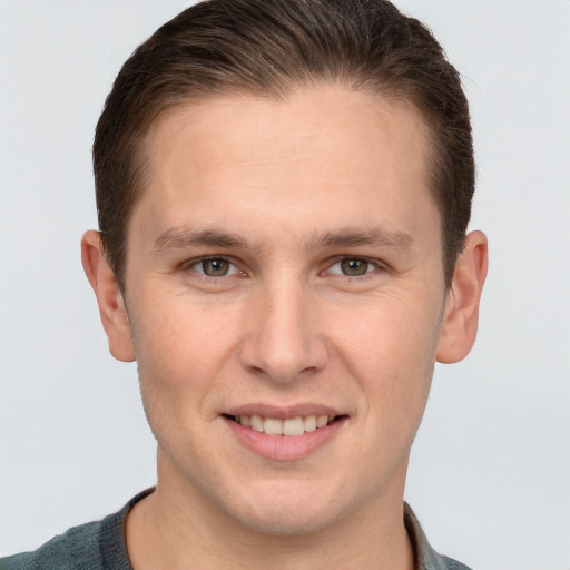 Joyful white young-adult male with short  brown hair and grey eyes