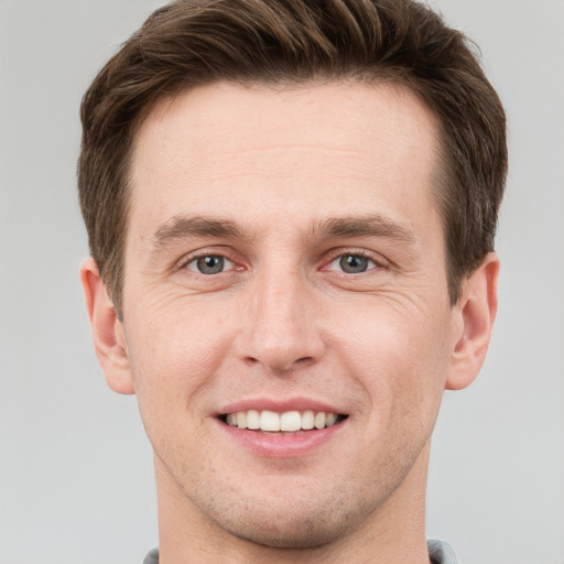 Joyful white young-adult male with short  brown hair and grey eyes