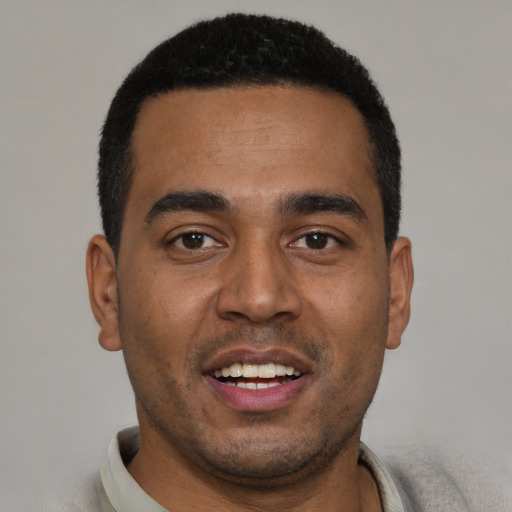 Joyful black young-adult male with short  black hair and brown eyes