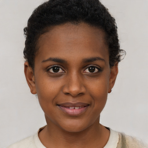 Joyful black young-adult female with short  black hair and brown eyes