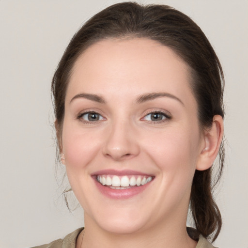 Joyful white young-adult female with medium  brown hair and grey eyes