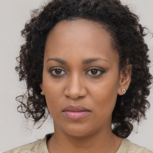 Joyful black young-adult female with long  brown hair and brown eyes