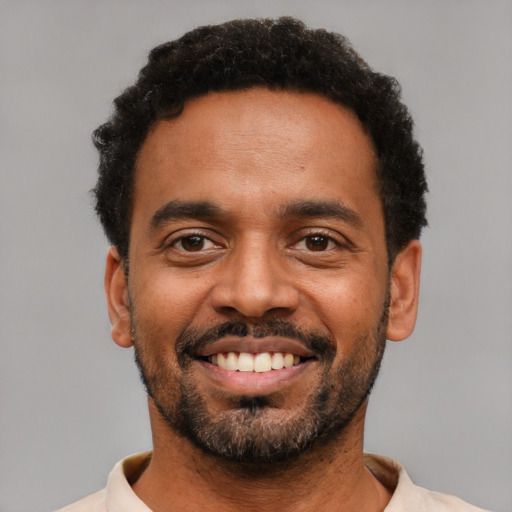 Joyful black young-adult male with short  black hair and brown eyes
