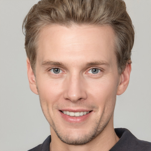 Joyful white young-adult male with short  brown hair and grey eyes