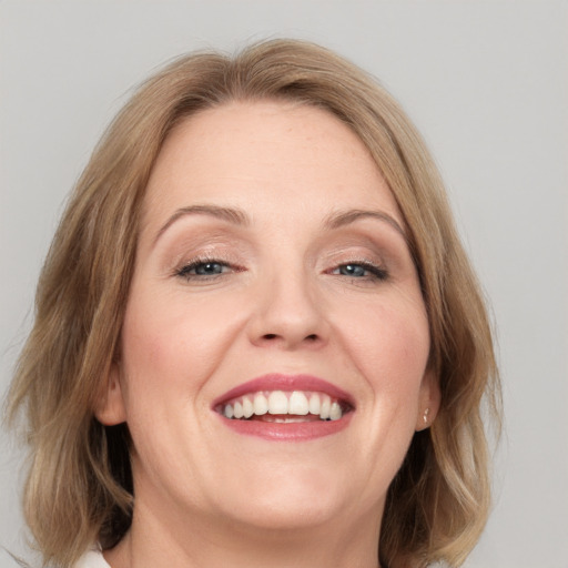 Joyful white adult female with medium  brown hair and blue eyes