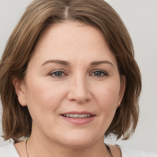 Joyful white adult female with medium  brown hair and grey eyes