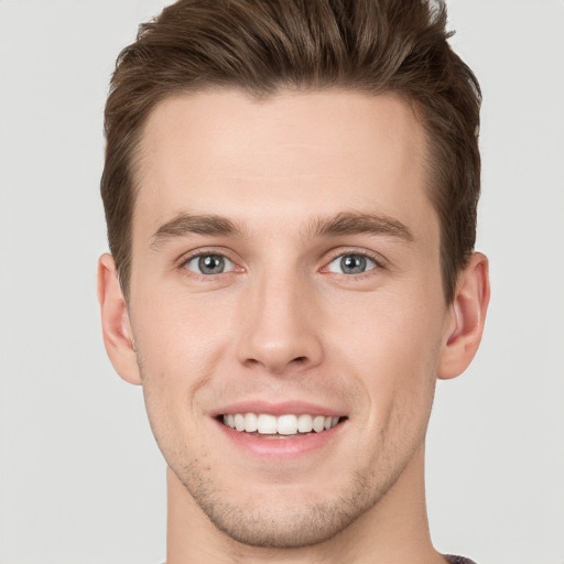 Joyful white young-adult male with short  brown hair and grey eyes