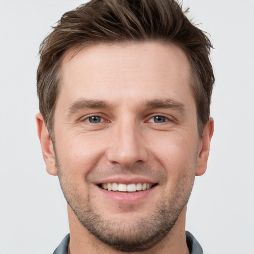 Joyful white young-adult male with short  brown hair and grey eyes