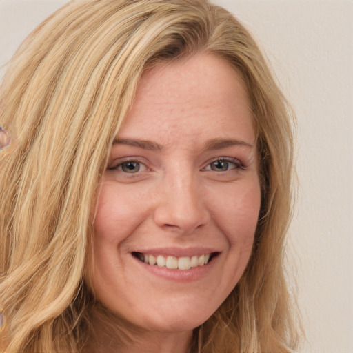 Joyful white adult female with long  brown hair and blue eyes