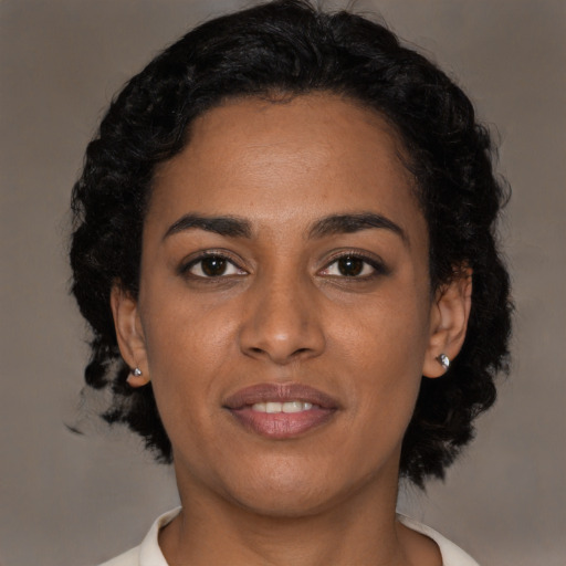 Joyful black young-adult female with short  black hair and brown eyes