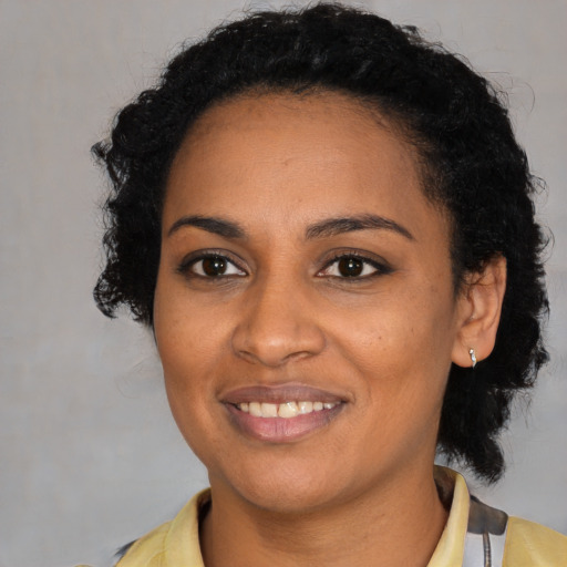 Joyful black young-adult female with short  black hair and brown eyes