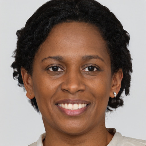 Joyful black young-adult female with short  brown hair and brown eyes