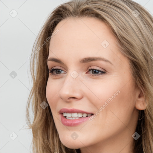 Joyful white young-adult female with long  brown hair and blue eyes