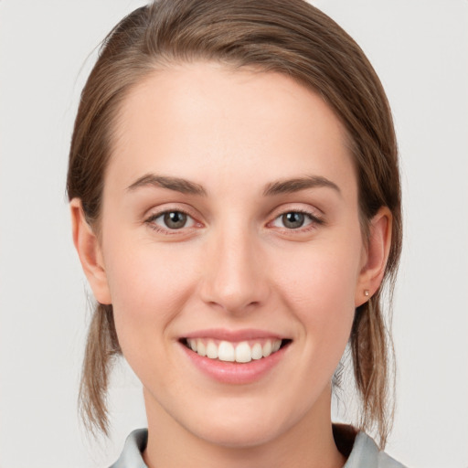 Joyful white young-adult female with medium  brown hair and grey eyes