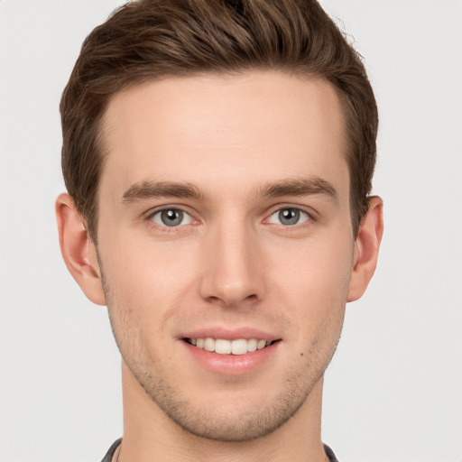 Joyful white young-adult male with short  brown hair and grey eyes