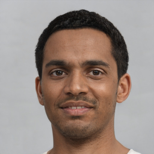 Joyful black young-adult male with short  black hair and brown eyes