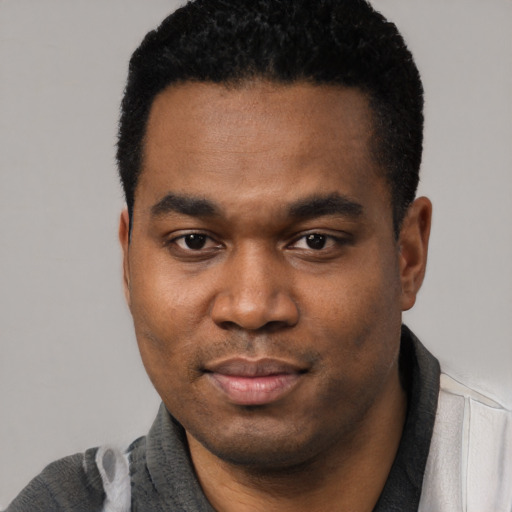 Joyful black young-adult male with short  black hair and brown eyes