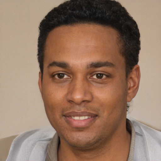 Joyful black young-adult male with short  black hair and brown eyes