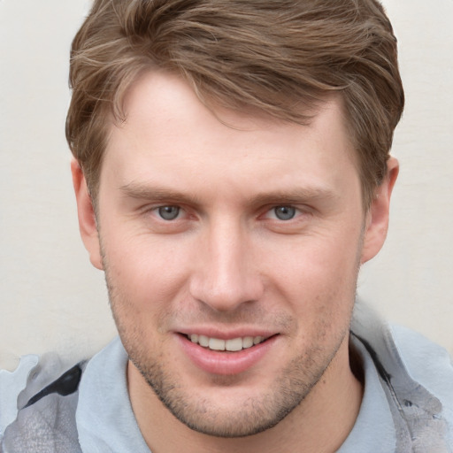 Joyful white young-adult male with short  brown hair and grey eyes