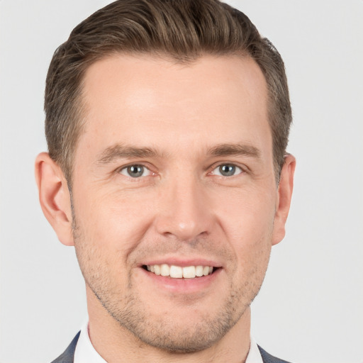 Joyful white young-adult male with short  brown hair and grey eyes