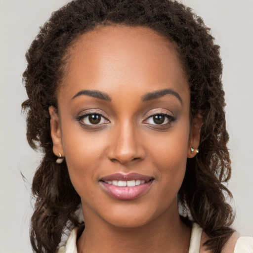 Joyful black young-adult female with long  brown hair and brown eyes