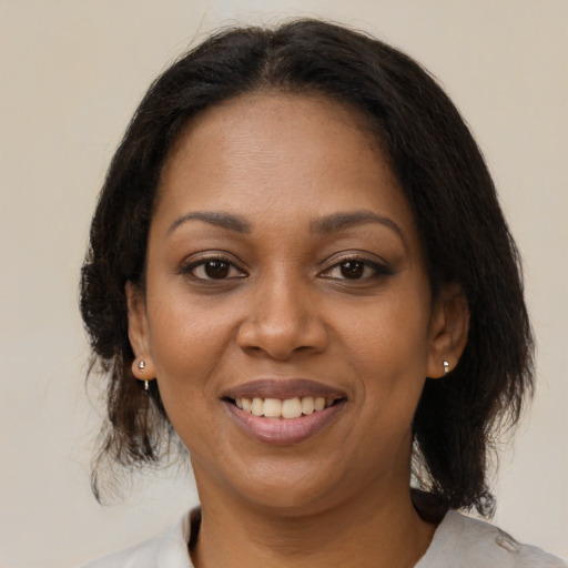 Joyful black adult female with medium  brown hair and brown eyes