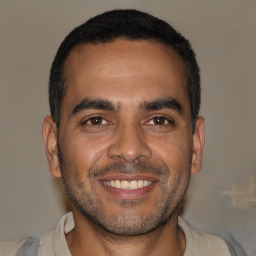Joyful black young-adult male with short  brown hair and brown eyes