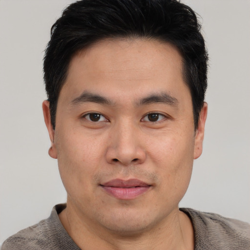 Joyful asian young-adult male with short  brown hair and brown eyes