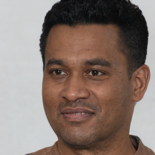 Joyful black young-adult male with short  black hair and brown eyes