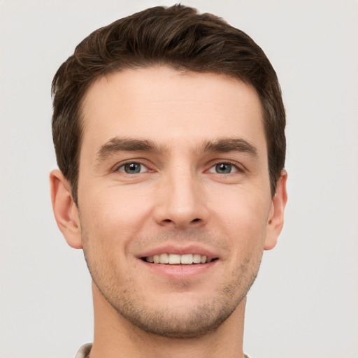 Joyful white young-adult male with short  brown hair and grey eyes