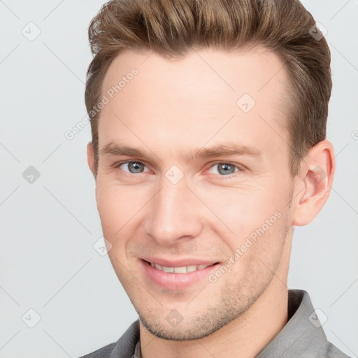 Joyful white young-adult male with short  brown hair and grey eyes