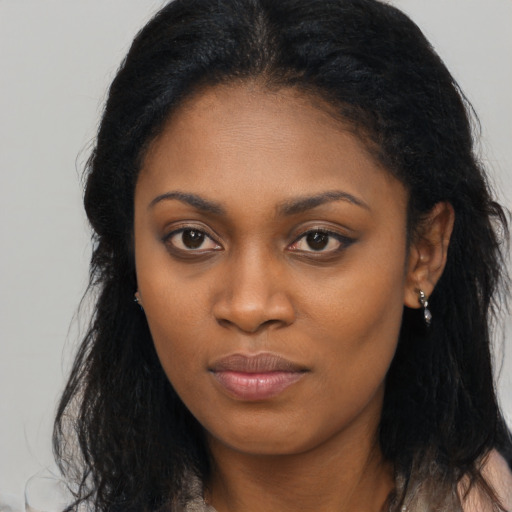 Joyful black young-adult female with long  brown hair and brown eyes