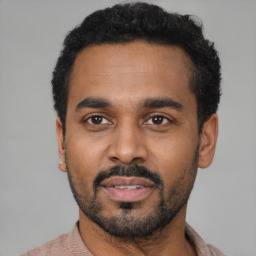 Joyful latino young-adult male with short  black hair and brown eyes