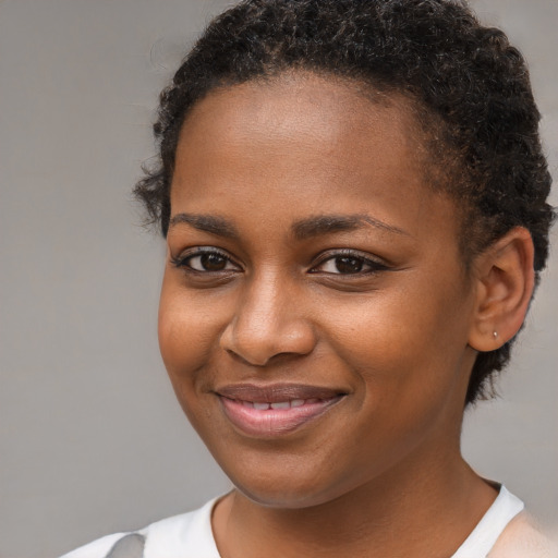 Joyful black young-adult female with short  brown hair and brown eyes